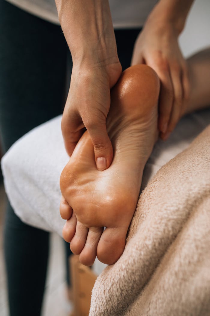 Hands massaging a foot to provide relaxation and promote wellness indoors.