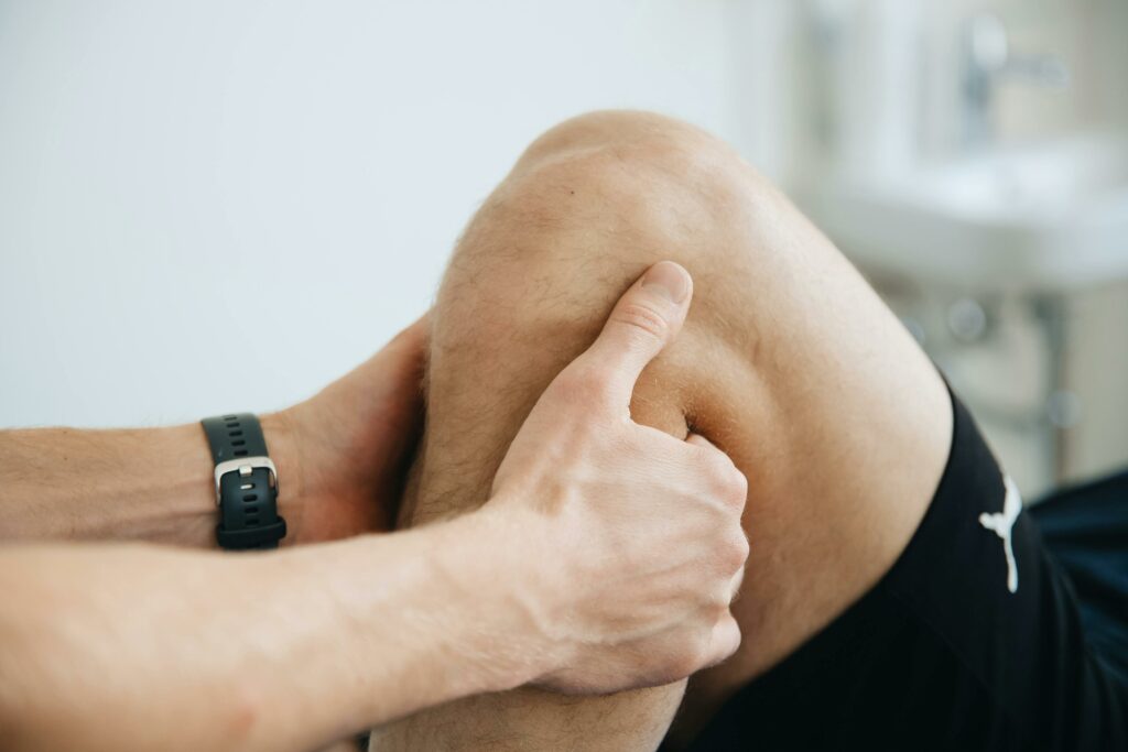 Close-up of a physiotherapist massaging a patient's knee during therapy.